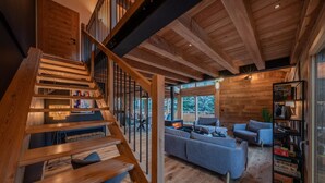 A wooden staircase leading to a living area with a fireplace, a sofa, and a bookshelf. - Chalet Le Refuge - Five Bedroom House, Sleeps 14 (La Salle-les-Alpes)