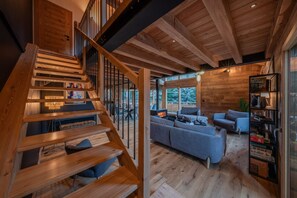 A wooden staircase leading to a living area with a fireplace, a sofa, and a bookshelf.