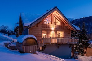 A wooden cabin with a balcony, a large barrel, and a snowy landscape.