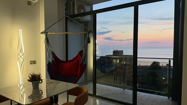 Un salon moderne avec une porte vitrée donnant sur un balcon qui offre une vue sur la mer.