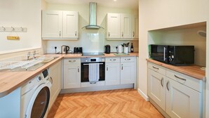 Eine kleine Küche mit Waschmaschine, Backofen, Mikrowelle und Holz Arbeitsplatten.