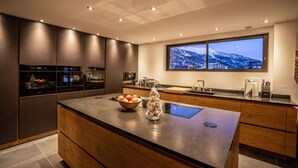 A modern kitchen with built-in appliances, a large island, and a window with a mountain view. - Beleza - Seven Bedroom House, Sleeps 15 (La Salle-les-Alpes)