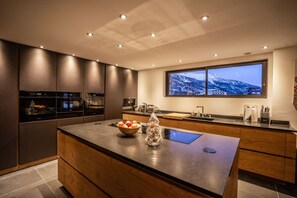 Una cocina moderna con electrodomésticos integrados, una isla grande y una ventana con vistas a la montaña.