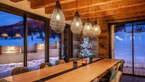 A dining area with a wooden table and chairs, hanging pendant lights, and a Christmas tree. - Beleza - Seven Bedroom House, Sleeps 15 (La Salle-les-Alpes)