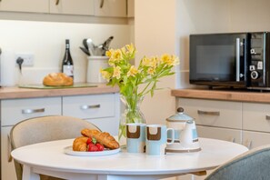 A dining table with croissants, strawberries, and a vase of flowers. - 1 Bed in Totland Bay (oc-a45313) (Freshwater)