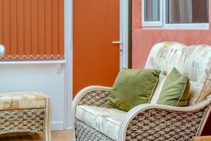 Une chaise en osier avec un coussin et un petit tabouret.