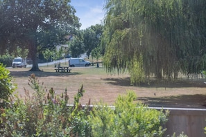 A park with a picnic table, a tree, and parked cars. - 1 Bed in Totland Bay (oc-a45313) (Freshwater)