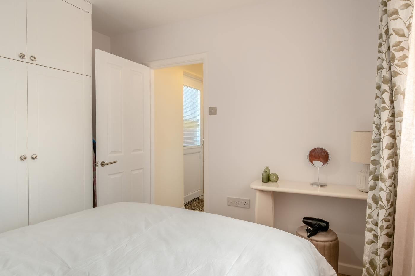 Een slaapkamer met een bed, een kledingkast, een kaptafel met spiegel en een radiator.