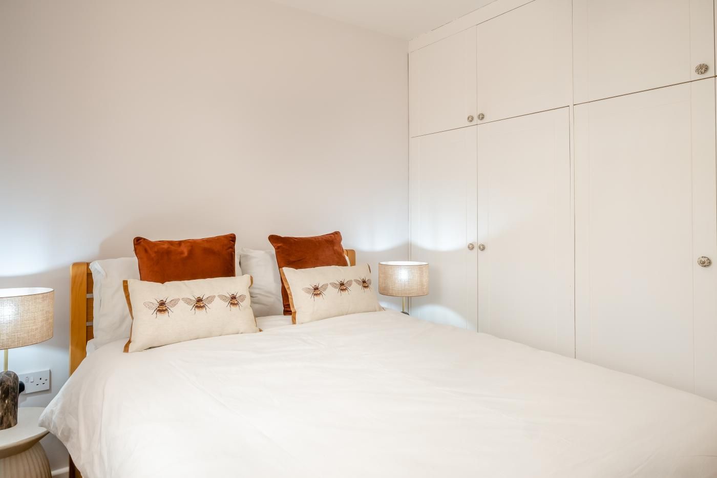 A bedroom with a bed, two bedside tables, a lamp, and a wardrobe.