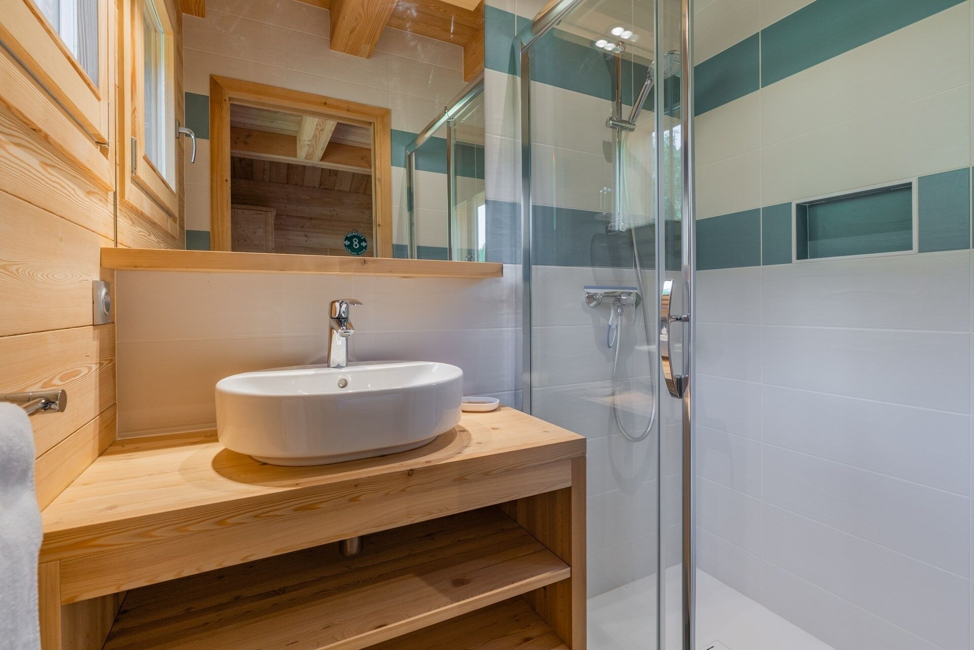 A bathroom with a wooden vanity, a white sink, and a glass shower enclosure.