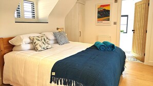 Ein Schlafzimmer mit einem Bett, Kissen, einer Decke, einem Gemälde und einer Holztür.