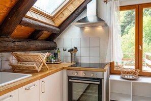 A kitchen with a skylight, wooden beams, a stove, and a window with a view of greenery. - Acolin - One Bedroom Apartment, Sleeps 6 (Briancon)
