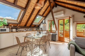 A modern kitchen with a glass dining table, wicker chairs, and a view of the outdoors. - Acolin - One Bedroom Apartment, Sleeps 6 (Briancon)