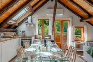 Un comedor con mesa de vidrio, sillas de mimbre y vistas al exterior.