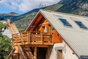 A wooden cabin with a balcony, a metal roof, and a mountain backdrop. - Acolin - One Bedroom Apartment, Sleeps 6 (Briancon)