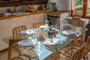 Un comedor con una mesa de vidrio dispuesta para cuatro personas, rodeado de sillas de mimbre.