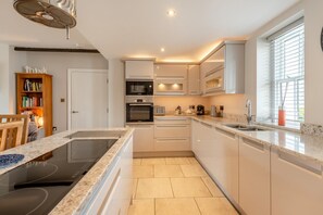 Eine moderne Küche mit Einbauherd, Backofen, Mikrowelle und einem großen Fenster für natürliches Licht.