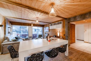 A modern interior with a wooden ceiling, a central island with bar stools, a sofa, and a TV mounted on the wall. - Europa - Three Bedroom Apartment, Sleeps 8 (Briancon)