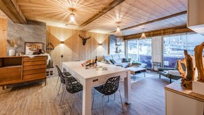 A wooden interior with a dining area, kitchen, and seating space. - Europa - Three Bedroom Apartment, Sleeps 8 (Briancon)