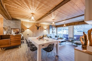 A wooden interior with a dining area, kitchen, and seating space. - Europa - Three Bedroom Apartment, Sleeps 8 (Briancon)