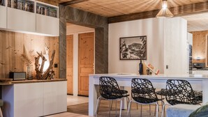 A modern kitchen with a central island, black woven chairs, and a wooden ceiling. - Europa - Three Bedroom Apartment, Sleeps 8 (Briancon)