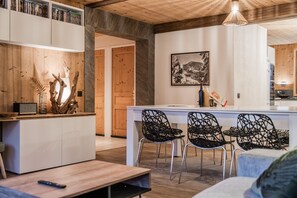 A modern kitchen with a central island, black woven chairs, and a wooden ceiling. - Europa - Three Bedroom Apartment, Sleeps 8 (Briancon)