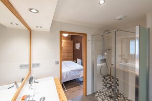 A modern bathroom with a large mirror, a shower with a glass door, and a wooden floor. - Baikal - Five Bedroom Apartment, Sleeps 9 (La Salle-les-Alpes)