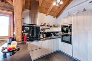 A modern kitchen with wooden beams, a built-in stove, and a microwave. - Baikal - Five Bedroom Apartment, Sleeps 9 (La Salle-les-Alpes)