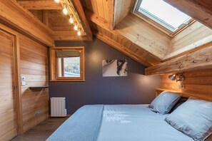A wooden cabin bedroom with a skylight, a bed, a radiator, and a small window. - Baikal - Five Bedroom Apartment, Sleeps 9 (La Salle-les-Alpes)