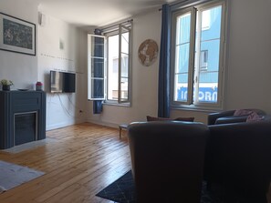 A living room with a fireplace, a television, and a large window with curtains. - Apartment in the heart of town (Bolbec)