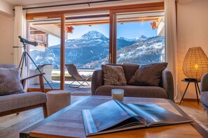 A living room with a mountain view, a tripod, a glass table, and a magazine. - Abela - Propriété d'exception, vue panoramique (Saint-Chaffrey)