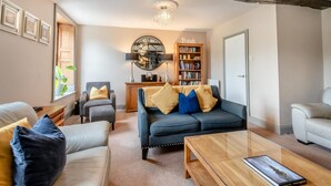 A living room with a sofa, armchairs, a coffee table, a bookshelf, and a chandelier. - 4 Bed in Keswick (oc-b45231) (Keswick)