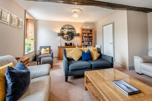 A living room with a sofa, armchairs, a coffee table, a bookshelf, and a chandelier. - 4 Bed in Keswick (oc-b45231) (Keswick)