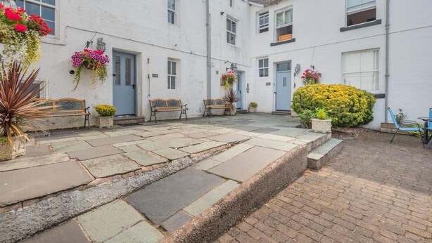 A courtyard with stone paving, benches, and flower baskets. - 4 Bed in Keswick (oc-b45231) (Keswick)