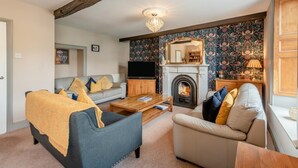 A living room with a fireplace, a television, and a sofa. - 4 Bed in Keswick (oc-b45231) (Keswick)