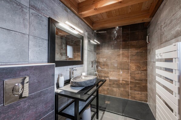 Un baño moderno con un lavabo de piedra, un espejo y zona de ducha.