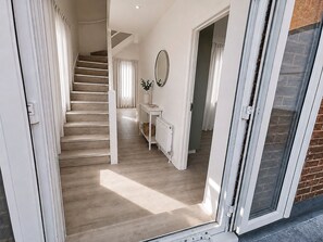 A staircase leading to a landing with a mirror and a small table with a vase. - Luxury 4-Bed Apartment (Northolt)