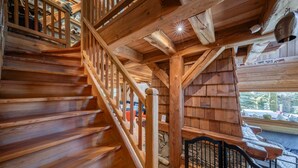 A wooden staircase with a railing, leading to a room with a stone wall and a view of the outdoors. - Echyllo - Six Bedroom Chalet, Sleeps 14 (Saint-Chaffrey)