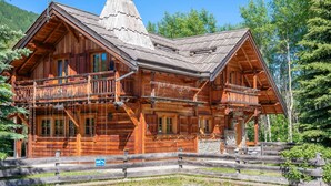 A wooden log cabin with a balcony, a chimney, and a fenced yard. - Echyllo - Six Bedroom Chalet, Sleeps 14 (Saint-Chaffrey)