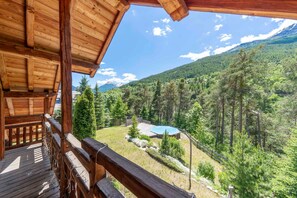 A wooden deck with a view of a mountain landscape and a pool area.