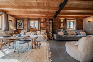 A cozy living room with wooden beams, a sofa, a coffee table, and a fireplace. - Galibier - Five Bedroom House, Sleeps 13 (Chantemerle)