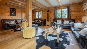 A log cabin interior with two sofas, a round chair, a wooden coffee table, and a cowhide rug. - Le Stam - Seven Bedroom House, Sleeps 15 (La Salle-les-Alpes)