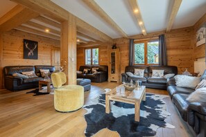 A log cabin interior with two sofas, a round chair, a wooden coffee table, and a cowhide rug.