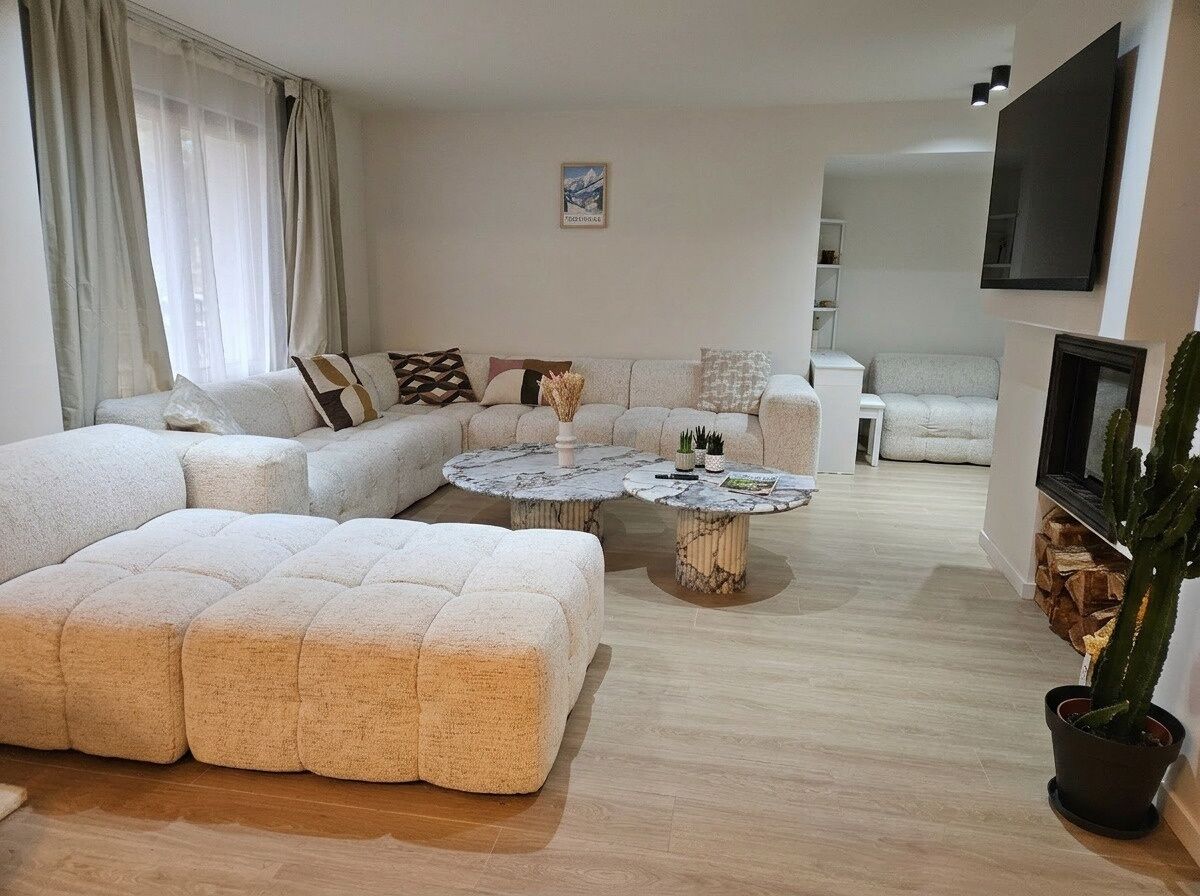 A modern living room with a sectional sofa, a round coffee table, and a potted plant.