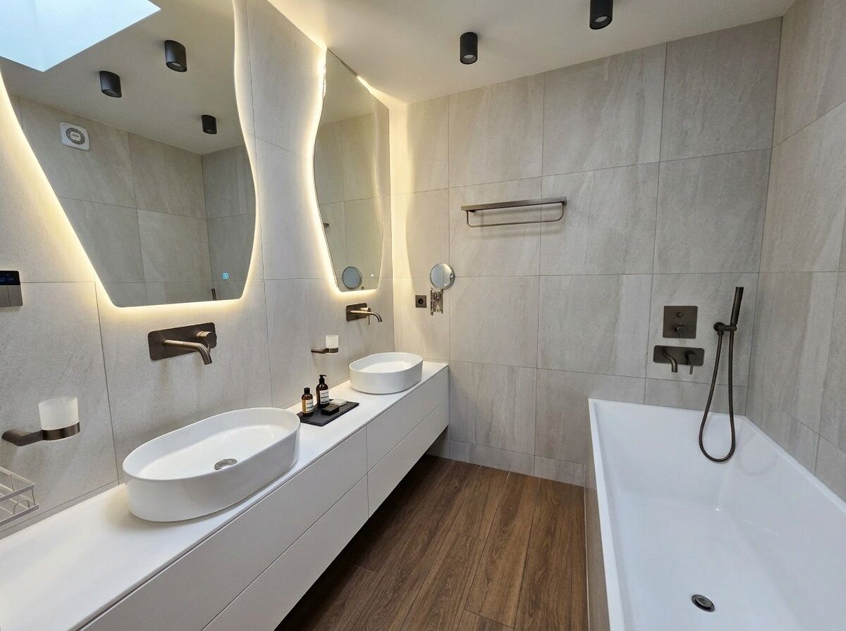 A modern bathroom with two sinks, a large mirror, a bathtub, and a shower.
