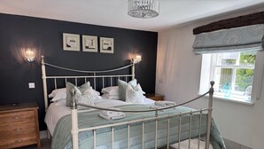 A bedroom with a white metal bed frame, a dark wall with three framed pictures, a bedside table, and a window with a view of greenery. - 1 Bed in Keswick (oc-b45234) (Keswick)