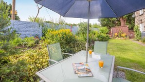 Eine Terrasse im Freien mit Tisch, Stühlen und Sonnenschirm.