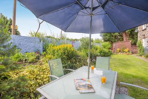 Eine Terrasse im Freien mit Tisch, Stühlen und Sonnenschirm.