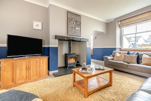 A living room with a television, wooden cabinet, sofa, and a fireplace. - 3 Bed in Keswick (oc-b45235) (Keswick)