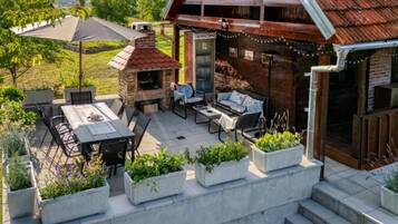 Une terrasse avec une table à manger, des chaises, un barbecue et des sièges d’extérieur.